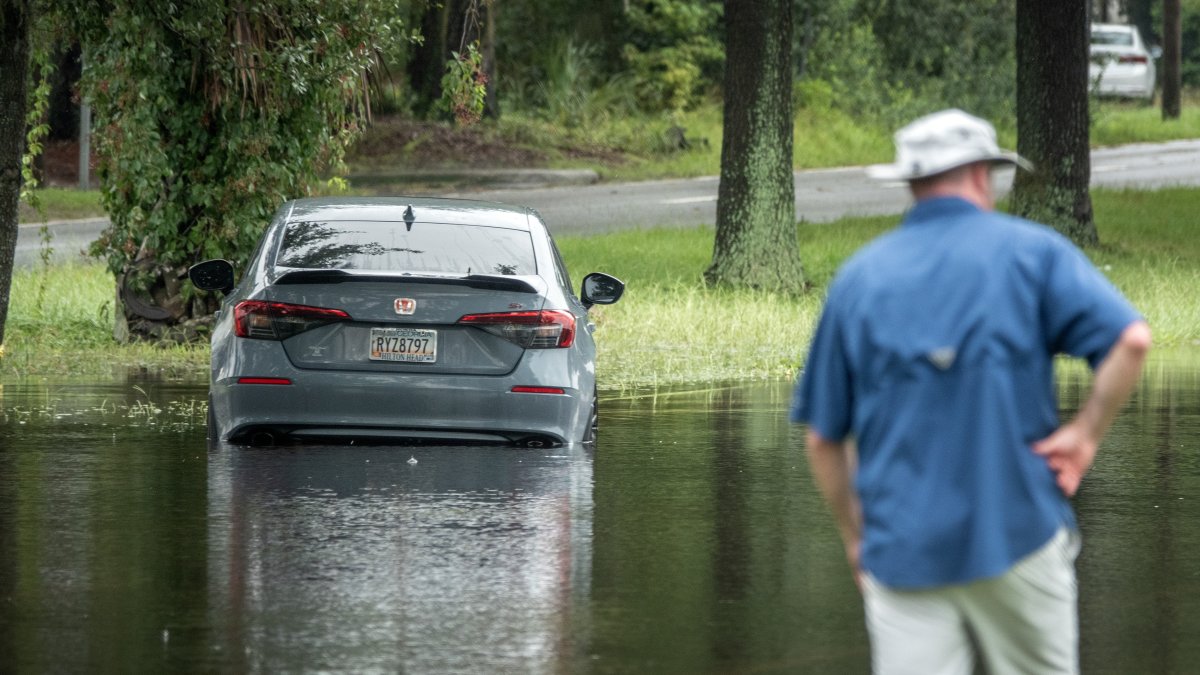 Un automóvil quedó atascado en una calle inundada tras una lluvia.