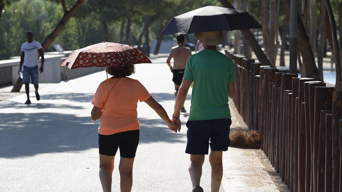 Una pareja pasea protegida por paraguas esta mañana en Madrid.