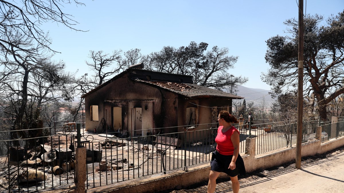 Una persona camina frente a una de las zonas afectadas por el fuego que se acercó peligrosamente a Atenas.