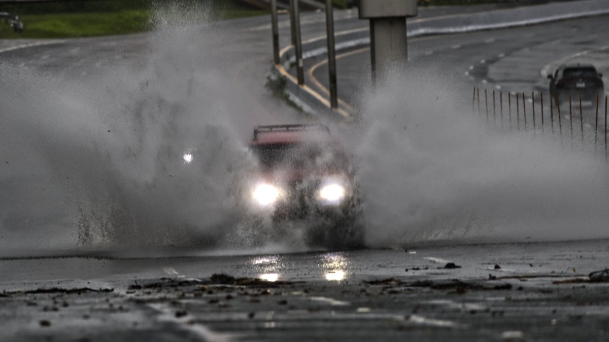 Un auto circula por una calle inundada por el paso del huracán Ernesto este miércoles, en San Juan, Puerto Rico.