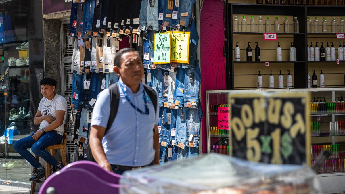 Un hombre junto a pantalones para la venta, en Caracas.