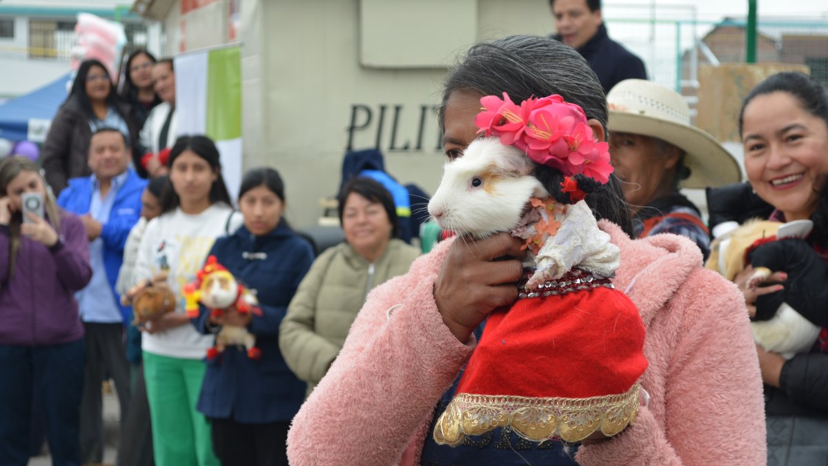 Una mujer muestra su mascota, vestida con el ropaje propio de su comunidad indígena andina.