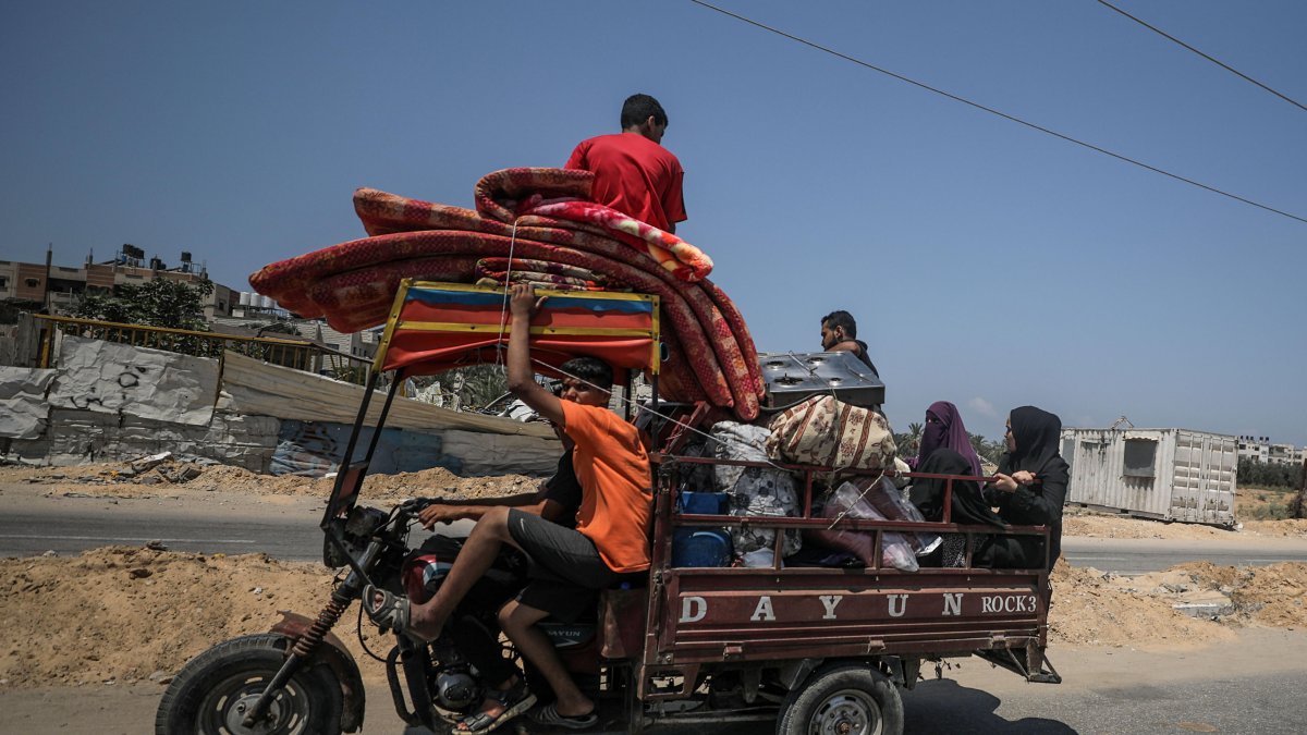 Palestinos desplazados internos huyen con sus pertenencias tras una orden de evacuación emitida por el ejército israelí, en el campo de refugiados de Al Maghazi, en la Franja de Gaza Central.