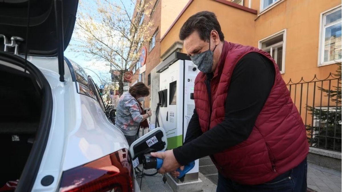 Vehículo.- Una persona pone carga a un carro eléctrico.