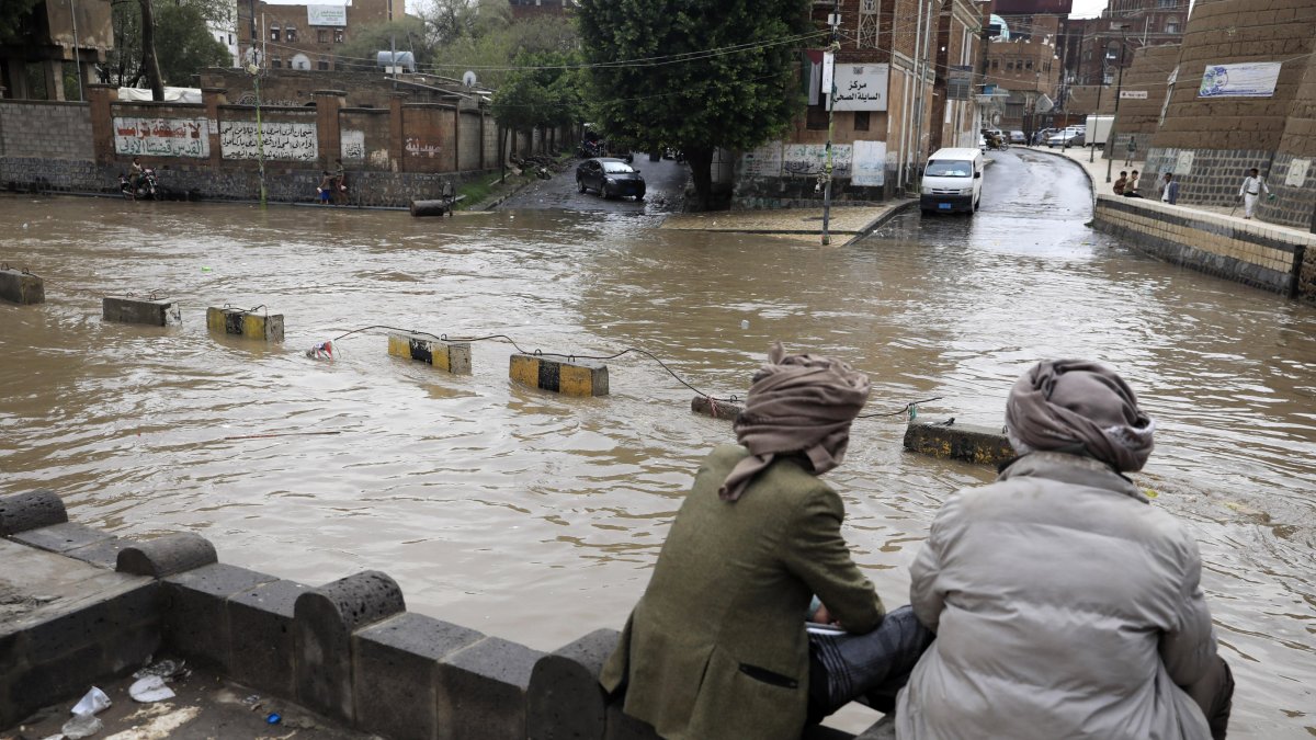 Un par de personas observan un calle bajo el agua. Lluvias en las últimas semanas han afectado a más de 250.000 personas solo en agosto.