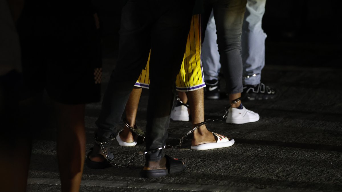 Migrantes esposados esperan en una fila luego de ser deportados de los Estados Unidos este martes, en el aeropuerto Marcos A. Gelabert en Ciudad de Panamá (Panamá).