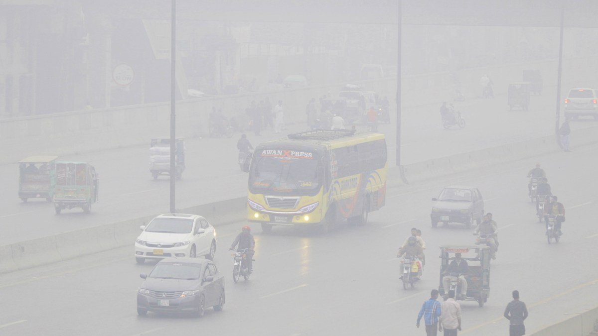 Personas viajan en coches y motocicletas bajo la nube de contaminación en Lahore.