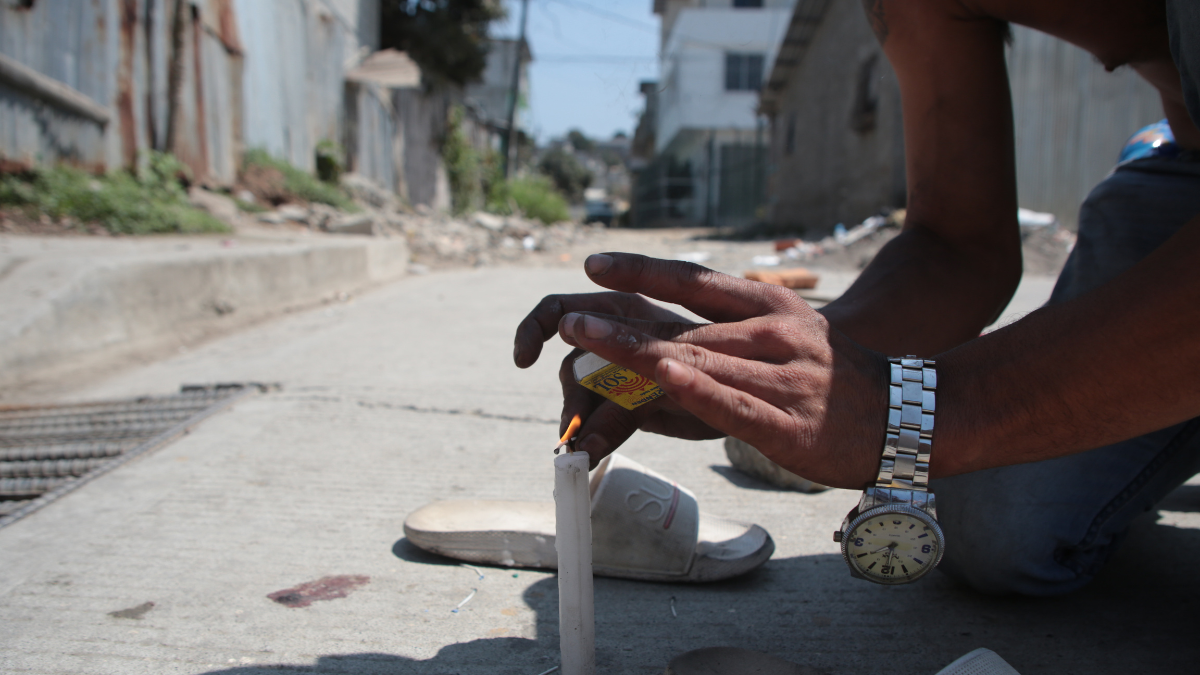 Un conocido de las víctimas en Nueva Prosperina enciende una vela en su memoria.