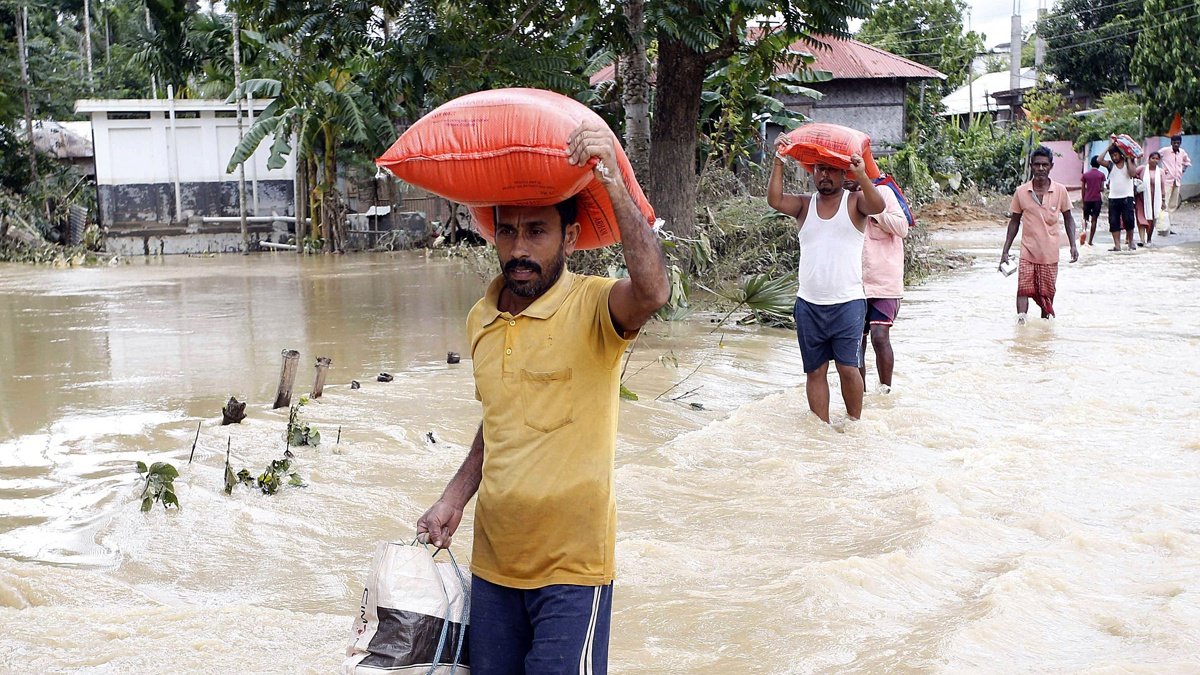 La gente camina entre el agua estancada en una vía en Amarpur Agartala, estado de Tripura, noreste de la India.