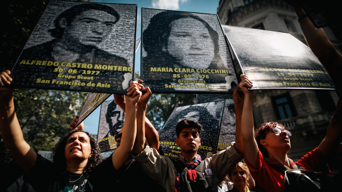 Manifestantes que muestran retratos de víctimas de la dictadura
