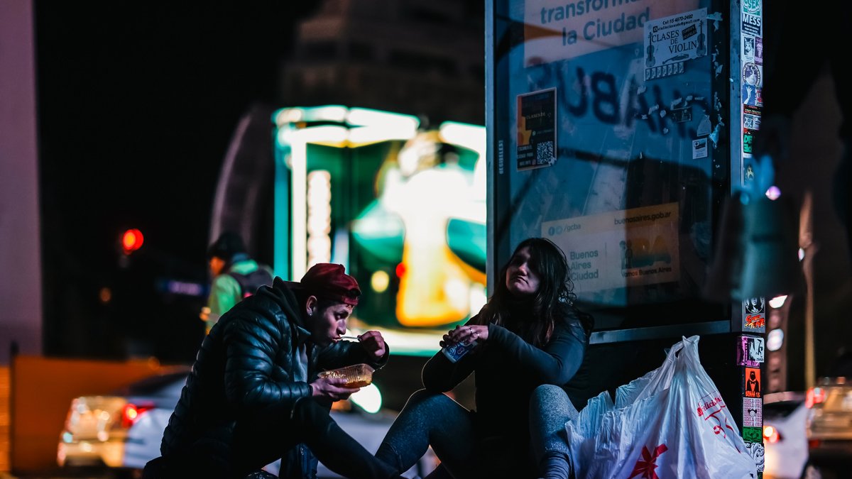 Habitantes de calle reciben alimentos frente al obelisco en Buenos Aires.