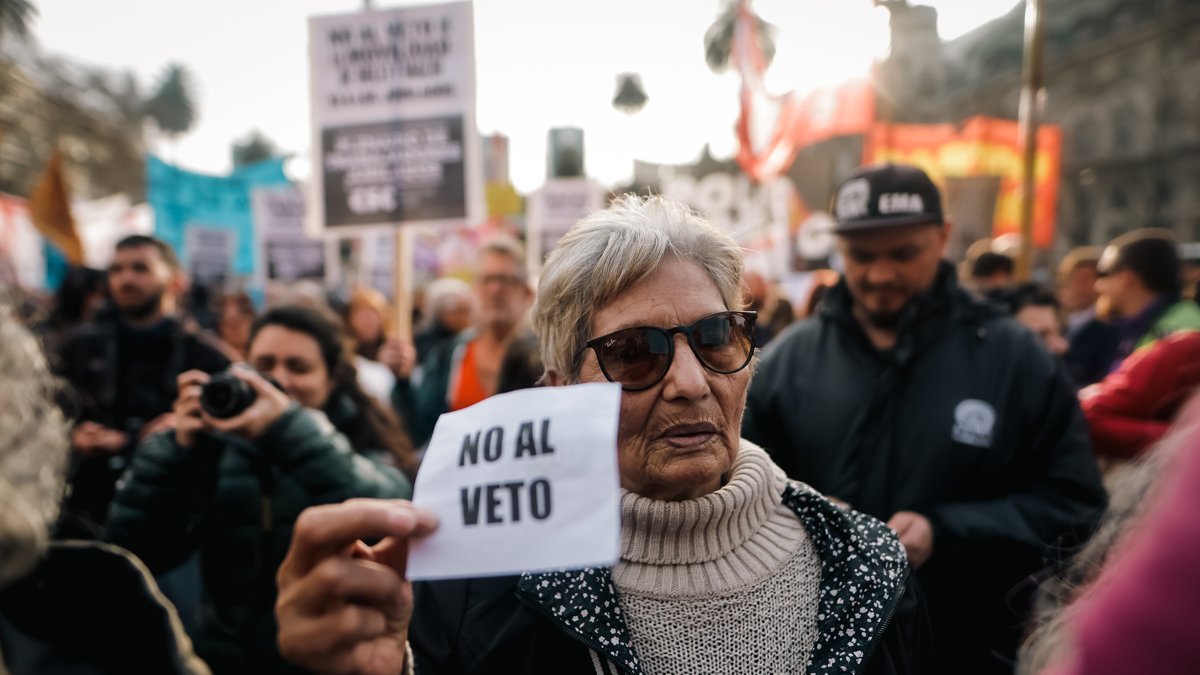 Una mujer que sostiene un cartel en una manifestación de jubilados el 28 de agosto de 2024