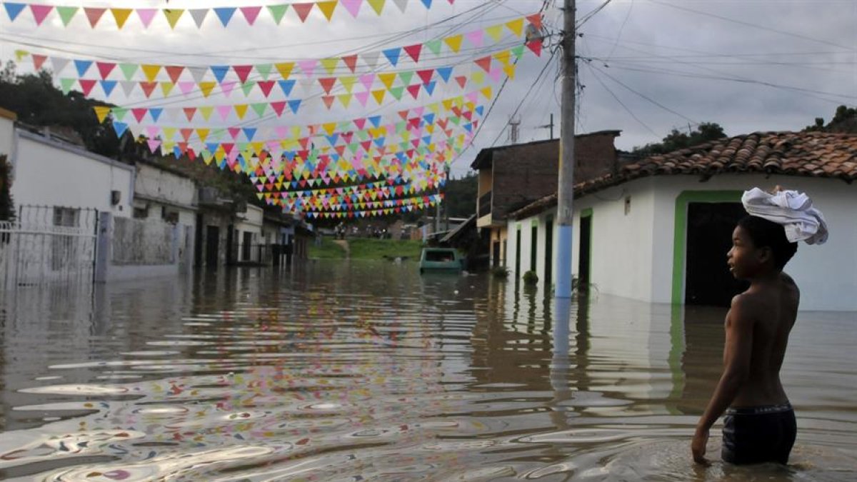 Archivo. Un niño camina por una calle inundada en Cali como consecuencia del fenómeno climatológico de 