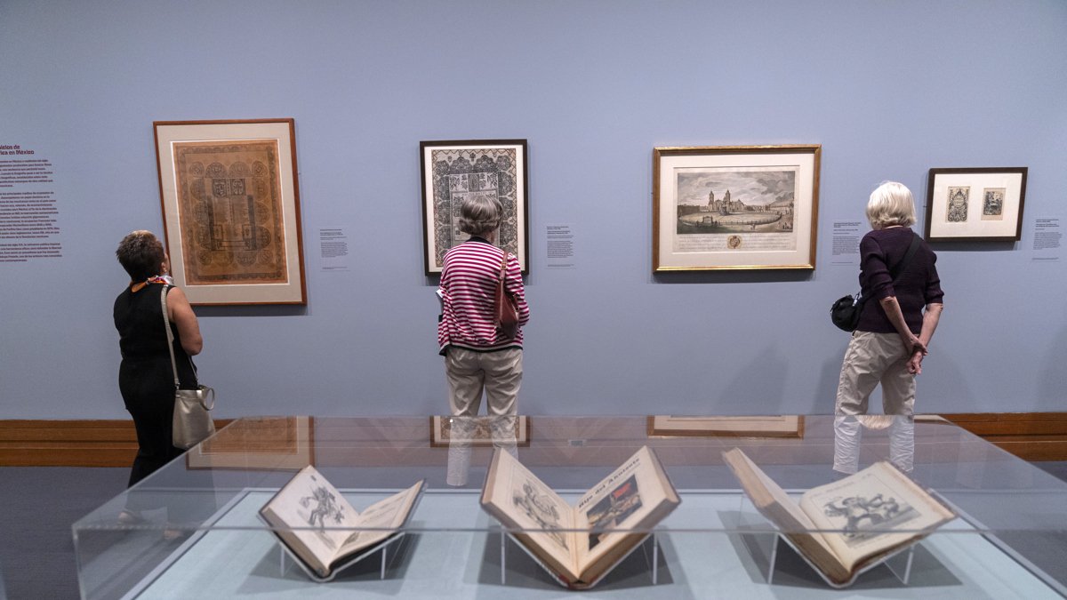 Personas observan unos carteles durante la exposición 'Grabados mexicanos a la vanguardia'.