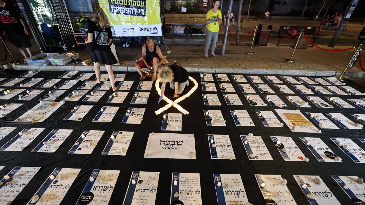 Los israelíes encienden velas cerca de los homenajes a los rehenes israelíes retenidos por Hamas en Gaza, durante una protesta pidiendo su liberación inmediata, en Tel Aviv.