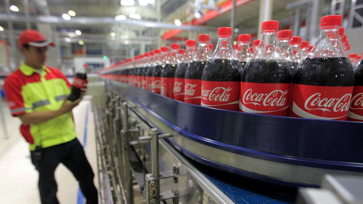Un trabajador se encuentra junto a los productos de Coca-Cola en la planta de Coca Cola.