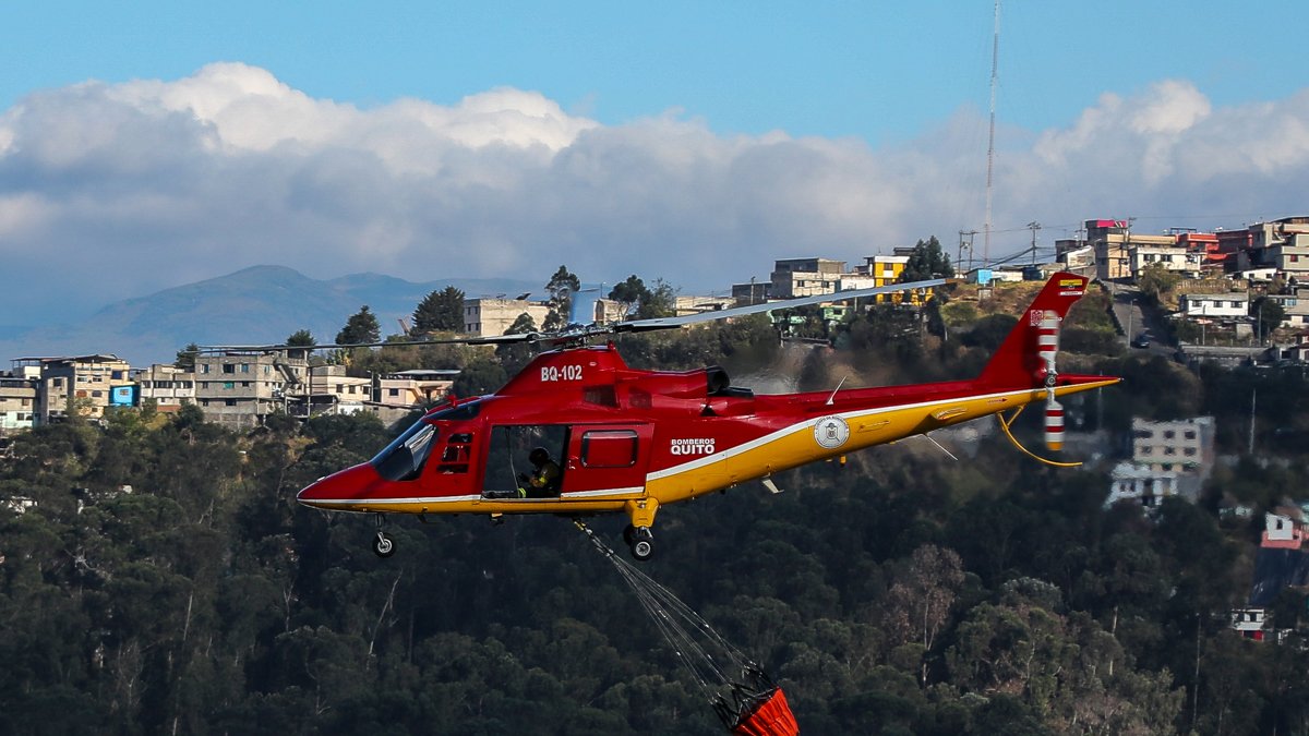 Fotografía de un helicóptero de bomberos lanzando agua para extinguir un incendio el 12 de septiembre de 2024 en las laderas del cerro El Panecillo, ubicado en el centro Histórico de Quito (Ecuador).