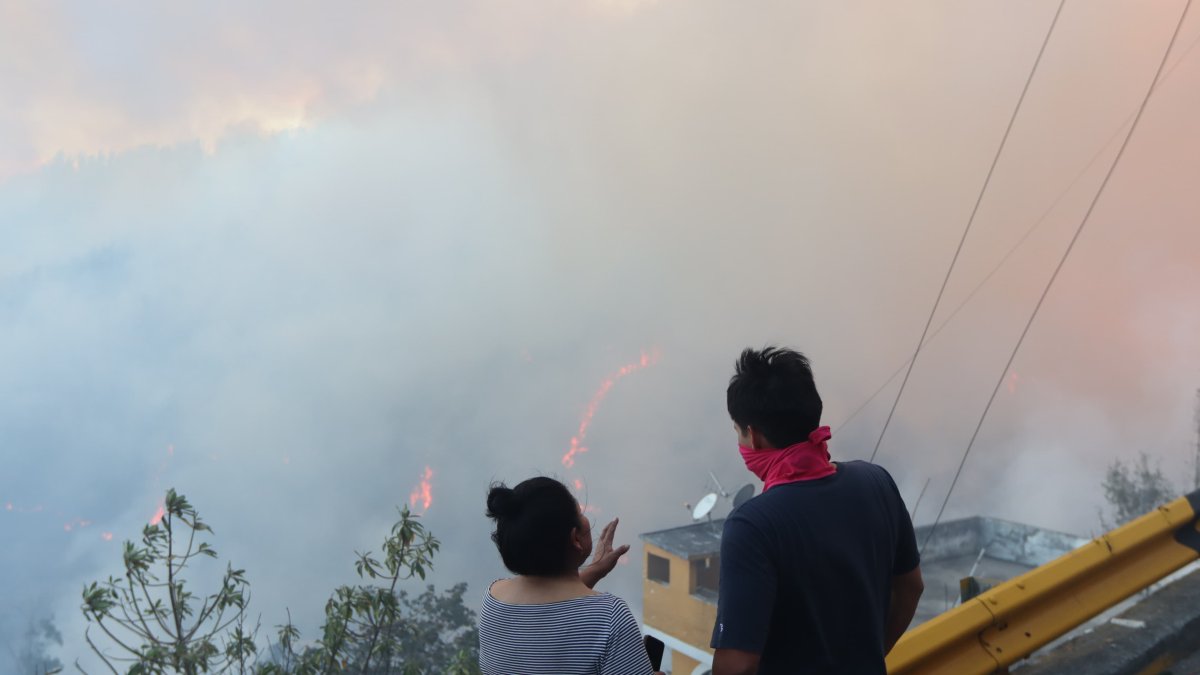 Dos pobladores observan las llamas sobre el bosque en Guápulo.