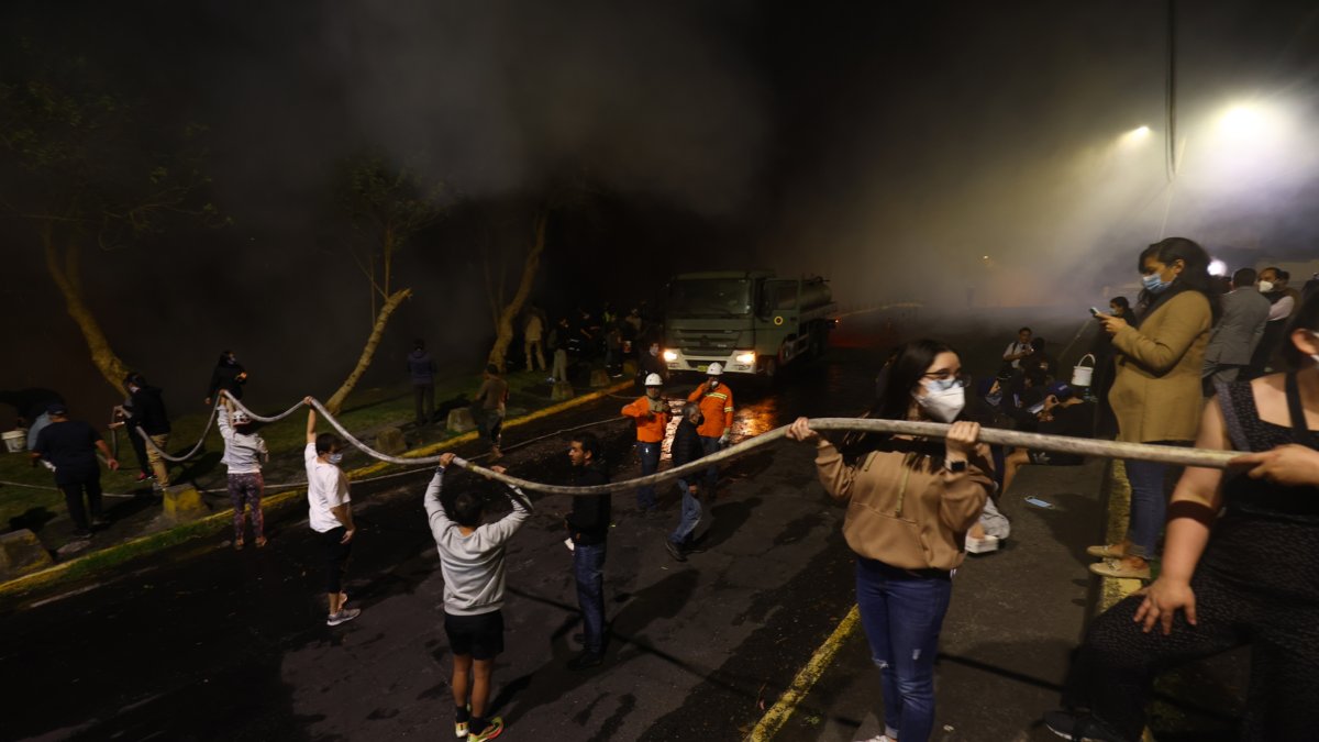 Vecinos de la avenida González Suárez y Manuel Barreto apoyan a las tareas de los bomberos para apaciguar el incendio en el sector, la noche de este martes 24 de septiembre.