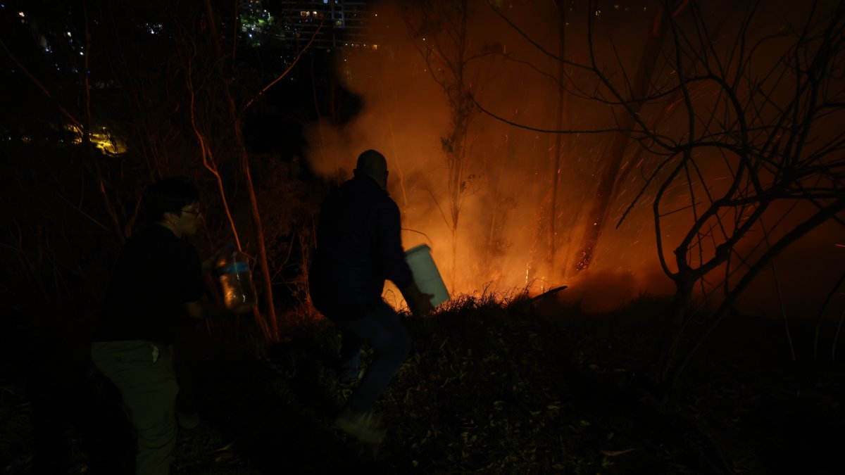 Vecinos de la avenida González Suárez y Manuel Barreto, en el norte de Quito, ayudan a los bomberos en las tareas de sofocar las llamas, la noche de este martes 24 de septiembre.