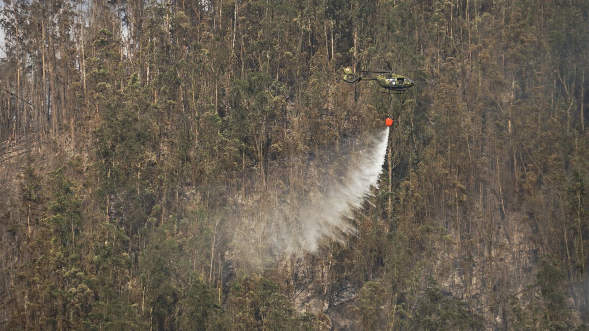 Helicópteros militares realizan descargas de agua en focos de fuego que se reactivaron en el cerro Auqui, nororiente de Quito, este miércoles 25 de septiembre.