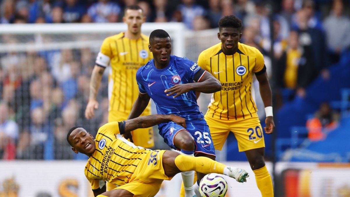 Pervis Estupiñán (piso) de Broghton defiende la pelota ante Moisés Caicedo (c) de Chelsea