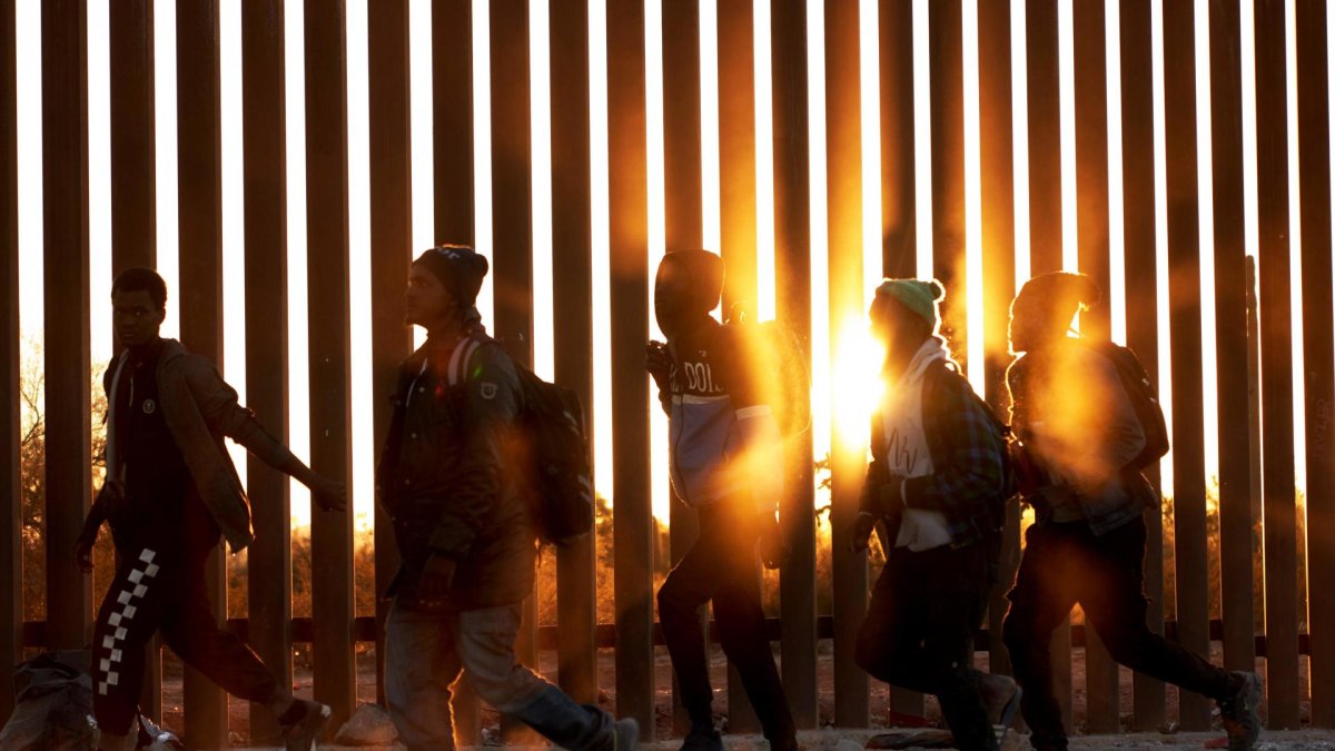 Fotografía de archivo de migrantes que caminan junto al muro en la frontera de EE.UU.