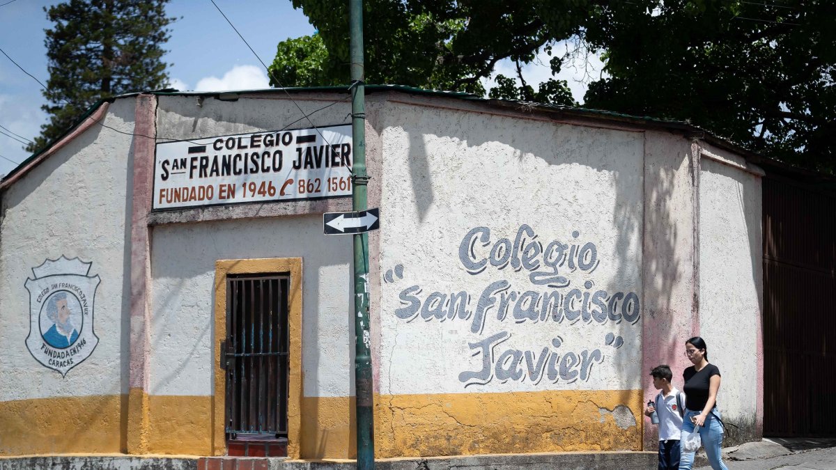 Una mujer camina junto a su hijo frente al colegio San Francisco Javier, este jueves en Caracas (Venezuela).