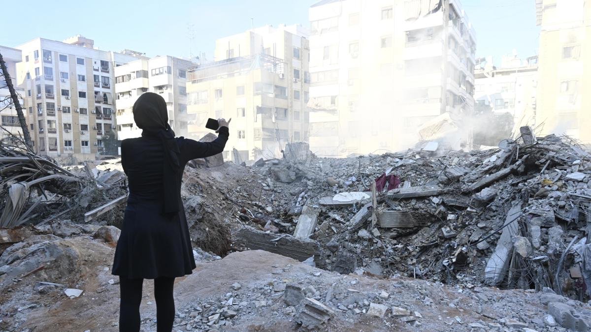 Una mujer toma una foto de un edificio destruido en el barrio de Haret Hreik,