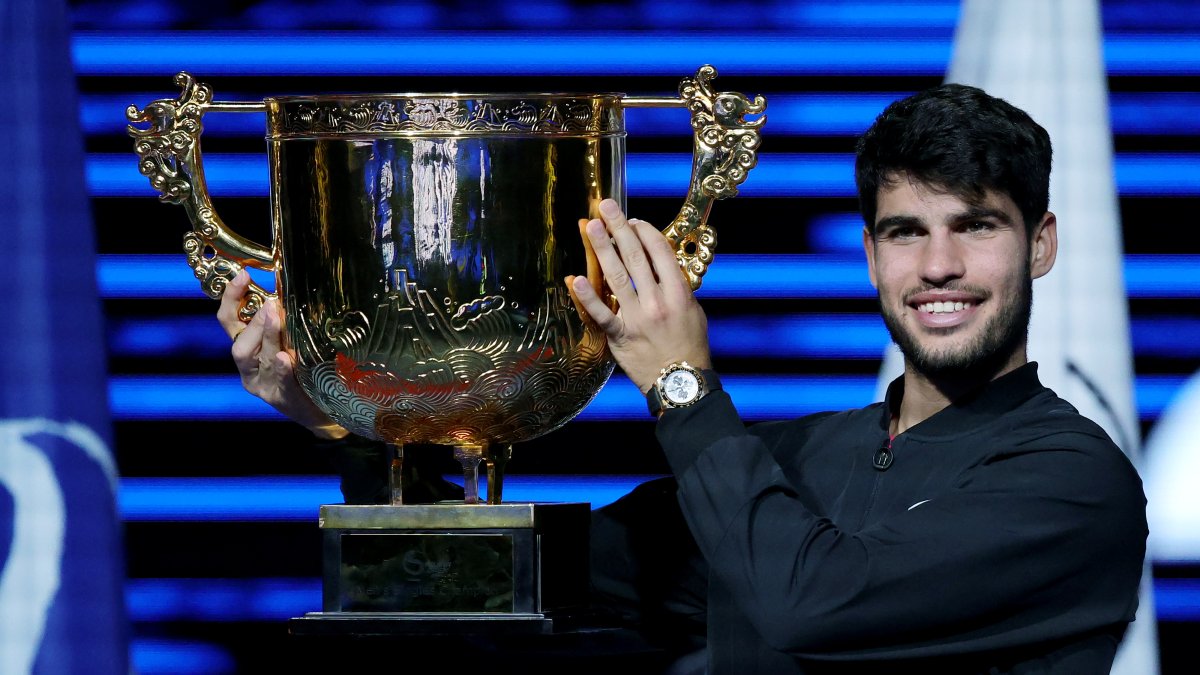 El español Carlos Alcaraz celebra con el trofeo tras vencer en la final del Open de China de Tenis al italiano Jannik Sinner.
