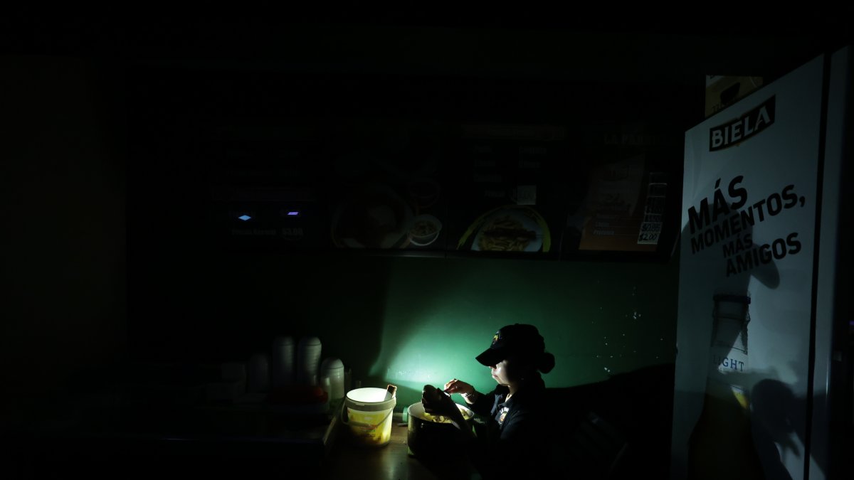 Comercio. Una trabajadora de un restaurante en Urdesa prepara un plato a la luz de una lámpara recargable, para atender a un cliente.