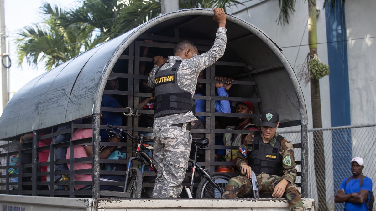 Guardias vigilan a haitianos que fueron detenidos en redadas de autoridades migratoria.