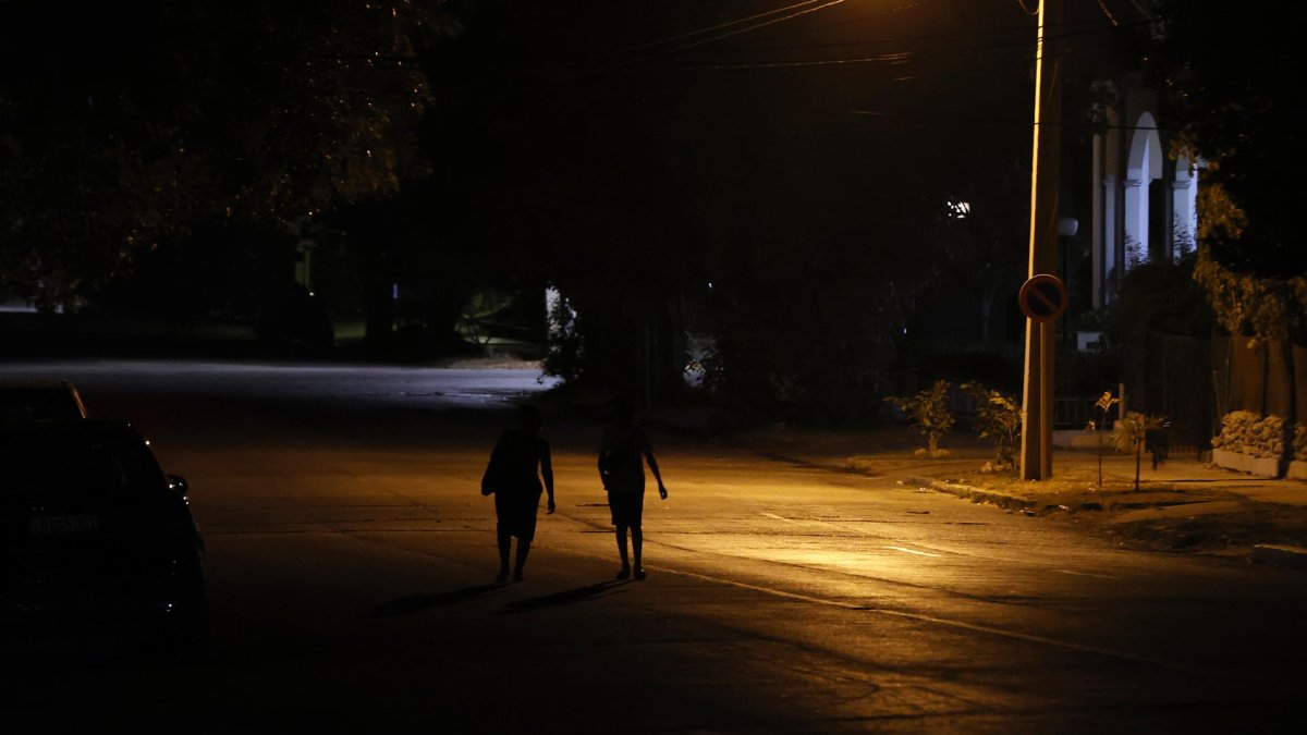 Varias personas caminan por una calle con poca iluminación en La Habana (Cuba).