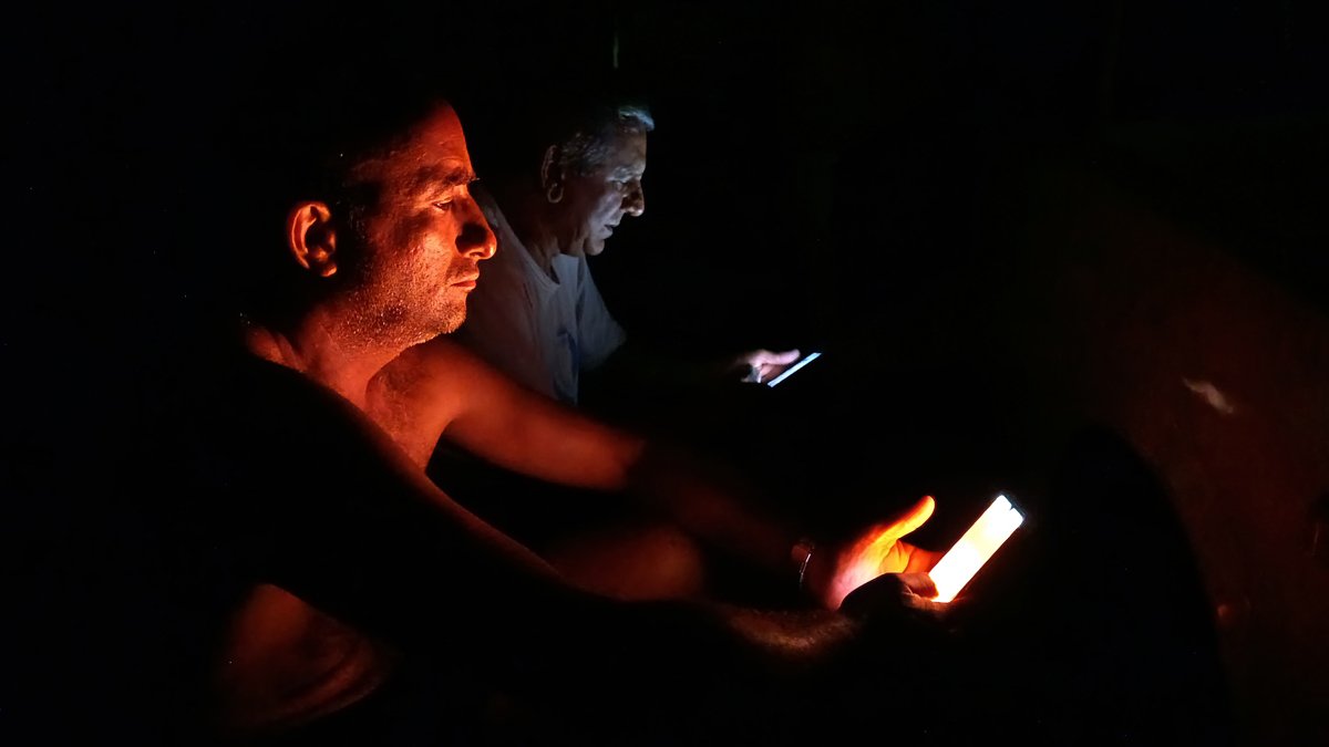 Personas observan su celular durante un apagón este viernes 18 de octubre, en La Habana, (Cuba).