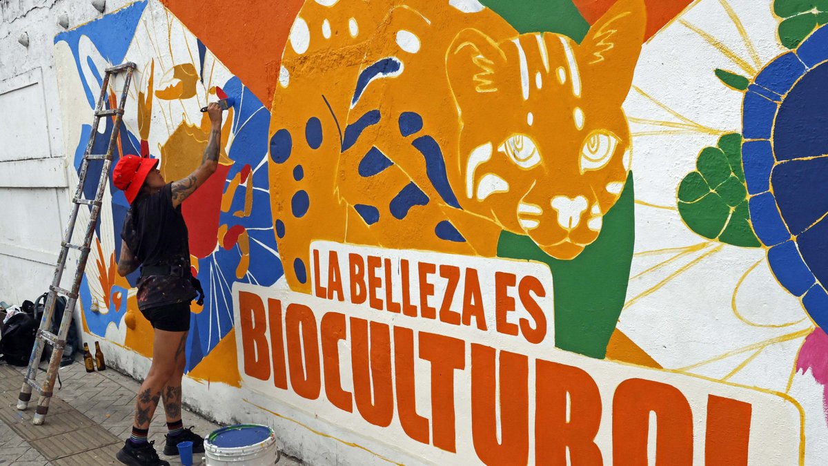 Una mujer pinta un mural este sábado 19 de octubre en Cali. La ciudad colombiana levantará este domingo el telón de la cumbre COP16.