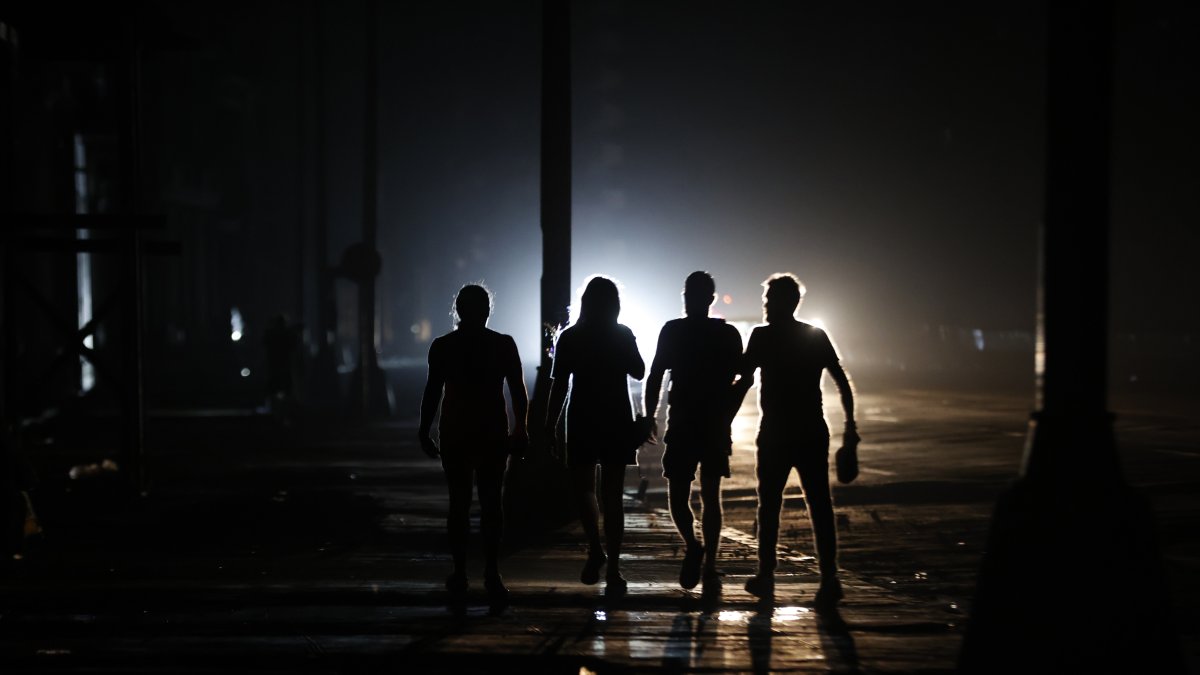 personas caminan por una calle durante un apagón este domingo, en La Habana (Cuba).