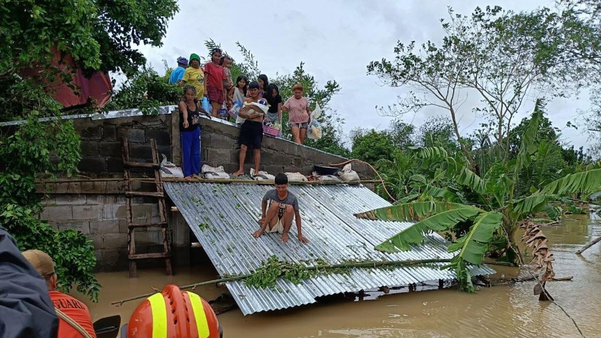 Un grupo de guardacostas acude en ayuda de una familia en una zona inundada.