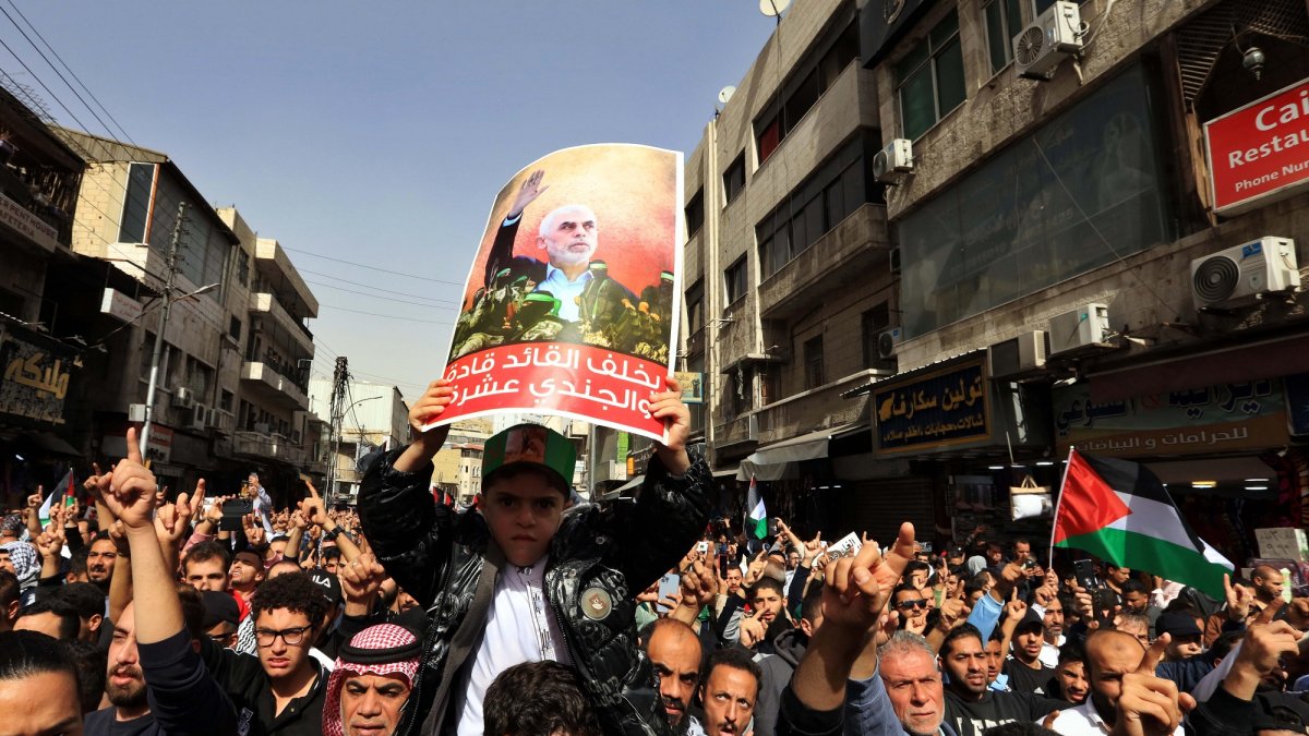 La gente grita consignas y porta pancartas que muestran al líder asesinado de Hamás, Yahya Sinwar, durante una protesta pro-palestina en Ammán, Jordania