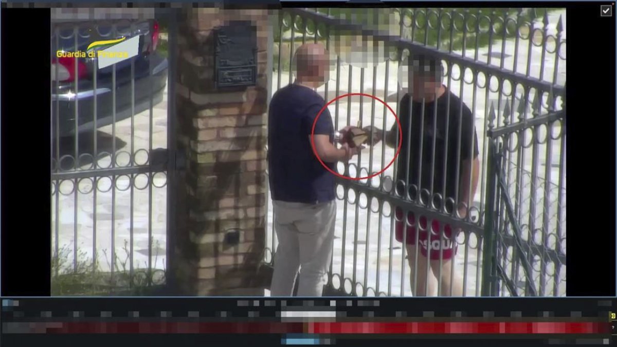 Roma. Un par de personas intercambian dinero tras una reja.