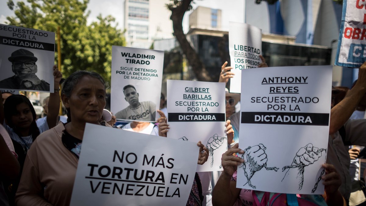 Personas con carteles que muestran imágenes de detenidos durante una manifestación frente a la sede del Ministerio de Servicio Penitenciario, en Caracas.