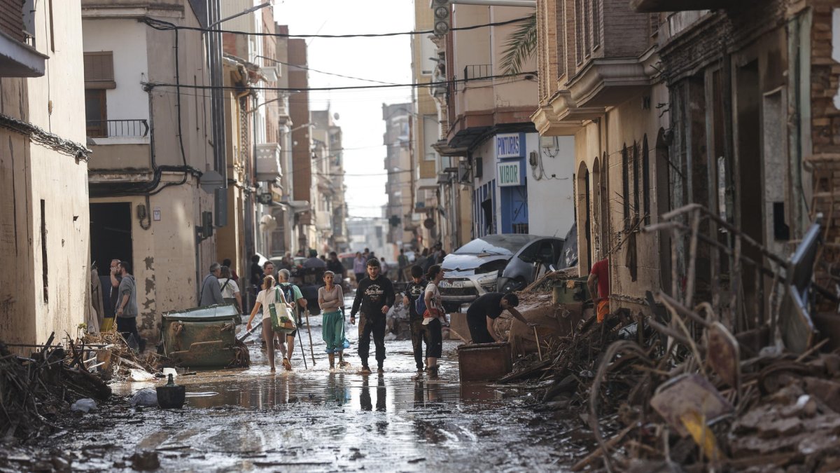 Varios grupos de personas recorren una zona afectada por las inundaciones generadas por el temporal que afecta a Valencia.