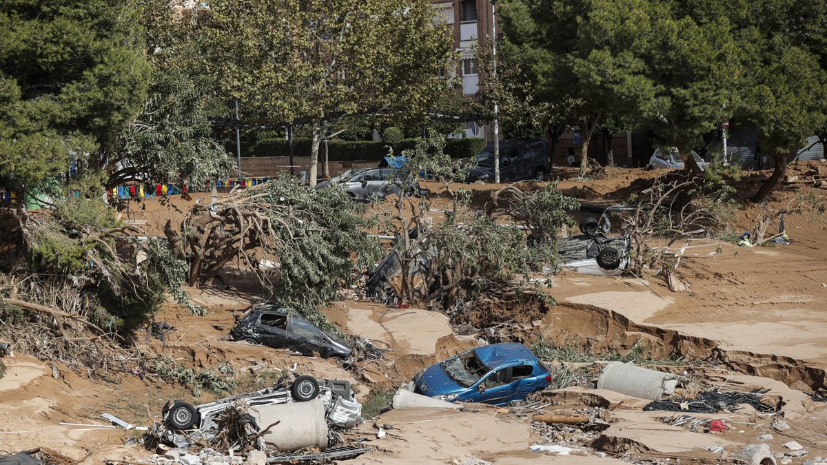 Varios vehículos permanecen semienterrados entre el lodo tras el paso de la DANA, este jueves en Paiporta, Valencia.