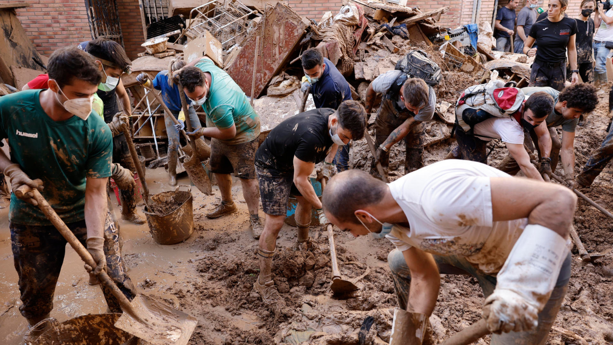 Varias personas retiran el lodo acumulado en una calle de la localidad valenciana de Paiporta, este sábado.