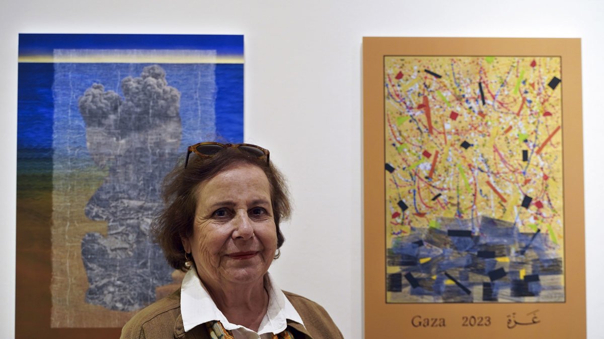 La artista palestina Vera Tamari posa junto a su obra en la exposición Pósteres de Gaza.