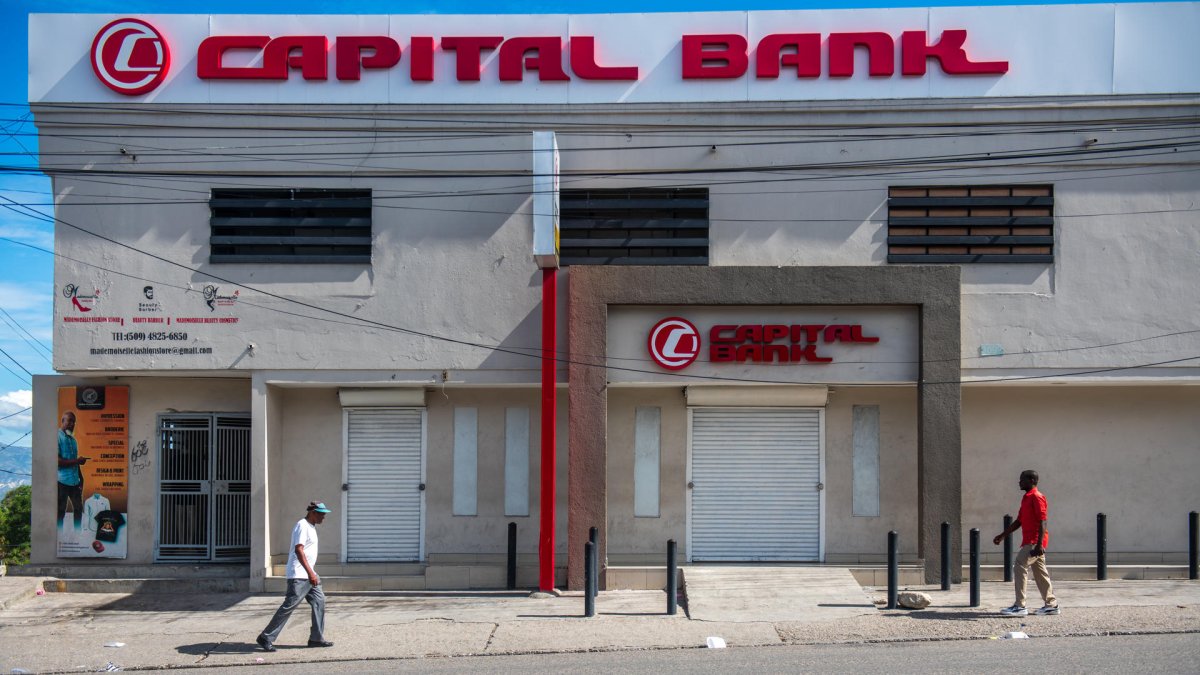 Personas caminan frente a locales de comercio cerrados este lunes en Puerto Príncipe (Haití).