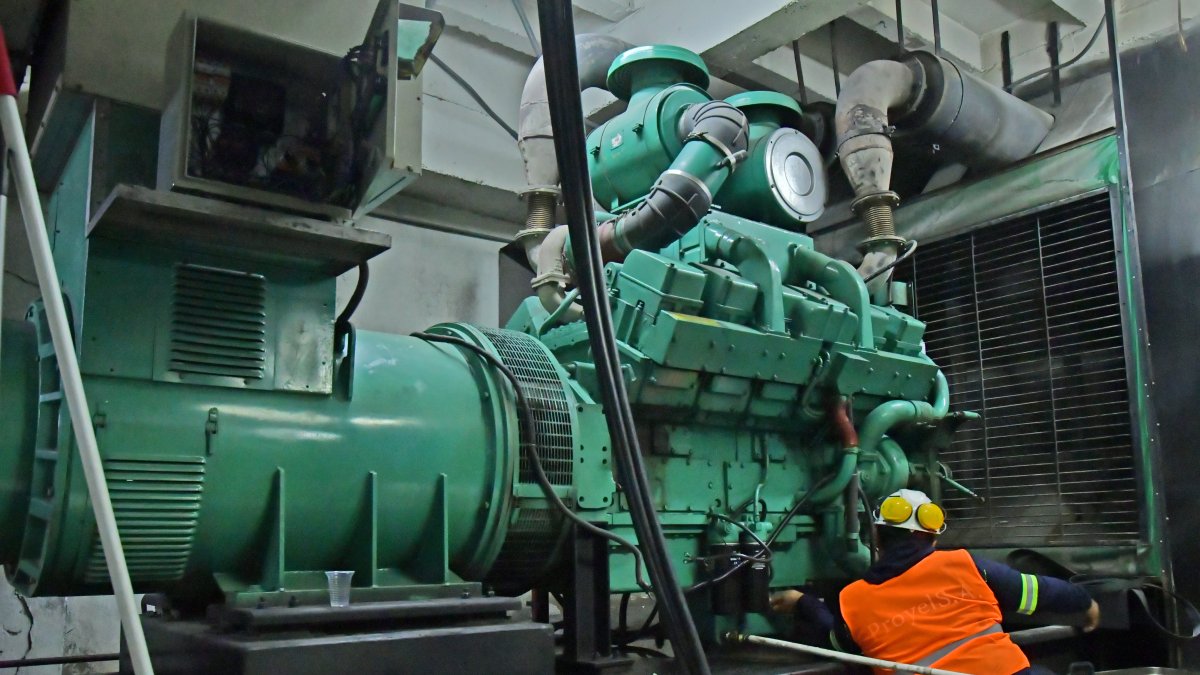 Empresa. Un trabajador da mantenimiento a un generador eléctrico industrial para que funcione las 24 horas.