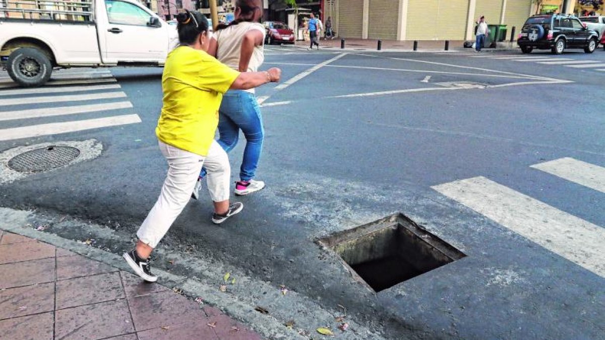 Ciudadanas cerca de caer en la alcantarilla por cruzar la calle.
