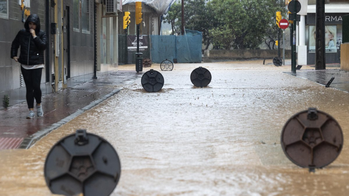 Alcantarillas abiertas en una calle de la barriada de Campanillas en Málaga, en la que el paso de la dana ha obligado a nuevos desalojos preventivos.