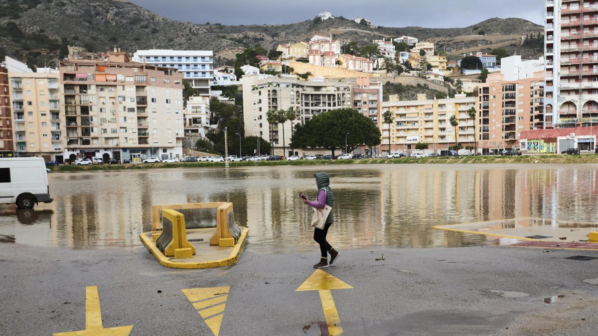Una mujer camina junto a un aparcamiento público anegado, en Cullera, ciudad que se ha visto afectada por fuertes lluvias esta madrugada aunque sin causar graves incidentes.