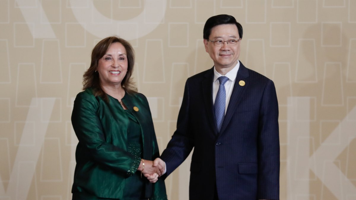 a presidenta de Perú, Dina Boluarte (i), saluda al jefe ejecutivo de Hong Kong, John Lee Ka-chiu (d).